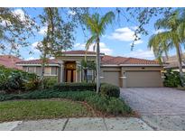 Charming single-story home with well-manicured lawn, mature landscaping, and a brick paved driveway leading to a two car garage at 11733 Delwick Dr, Windermere, FL 34786