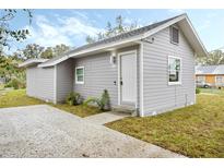 Charming gray home with a well-maintained lawn and a concrete walkway leading to the front door at 230 Hennis Rd, Winter Garden, FL 34787