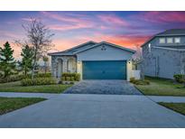 Charming single-story home boasts a well-manicured lawn, paver driveway, and a modern blue garage door at 4426 Davos Dr, Clermont, FL 34711