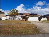 Charming single-story home with a well-maintained lawn, palm tree and solar panels at 550 Oak Branch Cir, Kissimmee, FL 34758