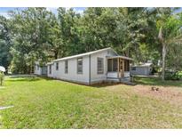 Charming home featuring a well-maintained lawn, mature trees, and a cozy screened-in porch at 630 N Nashua Ave, Fort Meade, FL 33841