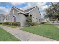 Charming home exterior featuring gray stucco, blue shutters, and well-maintained landscaping in a residential neighborhood at 13046 Island Breeze Ct, Orlando, FL 32824