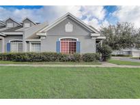 Charming home exterior featuring gray stucco, blue shutters, and well-maintained landscaping in a residential neighborhood at 13046 Island Breeze Ct, Orlando, FL 32824