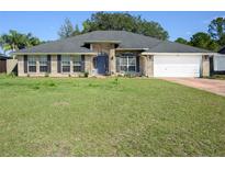 Charming single-story brick home with a well-manicured lawn, blue front door, and attached garage at 2454 Whitehorse St, Deltona, FL 32738