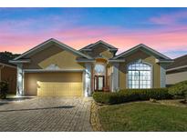 Charming single-story home features a manicured lawn, brick driveway, and an attached two-car garage at 322 High Vista, Davenport, FL 33837