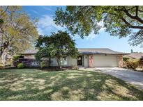 Charming single-story home with a well-manicured lawn, mature trees, and stone accents at 460 Forestwood Ln, Maitland, FL 32751