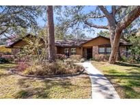 Charming single-story home featuring mature landscaping, a brick facade, and a welcoming walkway at 916 Puma Trl, Winter Springs, FL 32708