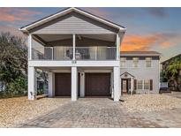 Two-story coastal home featuring a double garage, upper balcony, and manicured landscaping at 113 Avalon Dr, Ormond Beach, FL 32176