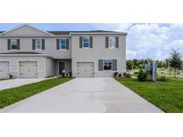 Two story townhome featuring gray exterior paint, a driveway, small bushes, and green grass at 3322 Wye Oak Dr, Apopka, FL 32703