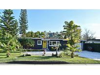 Charming single-story home featuring a vibrant yellow front door and lush tropical landscaping at 3714 Virginia Dr, Orlando, FL 32803