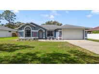 Charming single-story home with blue siding, well-manicured lawn, and a two-car garage at 607 S Glencoe Rd, New Smyrna Beach, FL 32168