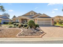 Charming single-story home with a manicured front yard and brick-paved driveway and neutral tan exterior at 8712 Sw 83Rd Cir, Ocala, FL 34481