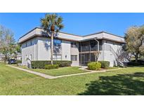 Well-maintained two-story condo building featuring manicured landscaping, a palm tree, and neutral paint scheme at 112 Windtree Ln # 203, Winter Garden, FL 34787