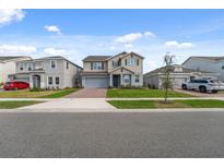 Two-story home featuring a neutral palette, attached garage, and manicured lawn at 1171 Lone Palm Way, St Cloud, FL 34771