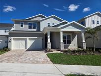 Charming two-story home with a two-car garage, brick driveway, and a welcoming front porch at 13217 Tollcross Way, Winter Garden, FL 34787