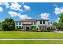 Stunning two-story home with a porte-cochere, lush landscaping, and a well-manicured lawn at 13643 Lake Cawood Dr, Windermere, FL 34786