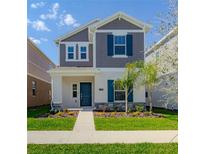 Charming two-story home with gray shingles, teal shutters, manicured lawn, and walkway at 6140 Shavasana Rd, Clermont, FL 34714