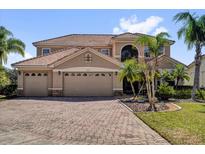 Elegant two-story home featuring a three-car garage, tile roof, and paver driveway at 2020 Imperial Eagle Pl, Kissimmee, FL 34746