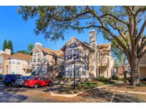 Inviting condo exterior featuring a chimney, tan siding, and mature shade trees at 675 Youngstown Pkwy # 258, Altamonte Springs, FL 32714
