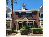 Charming brick townhouse with a manicured lawn, black shutters, and a inviting front porch at 9686 Cypress Pine St, Orlando, FL 32827