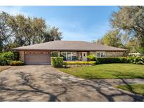 Charming single-story brick home featuring a well-manicured lawn and a two-car garage at 1321 Medinah Ct, Winter Park, FL 32792