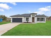 Charming single-story home featuring a well-maintained lawn and a gray two-car garage at 2480 Sw 147Th Lane Rd, Ocala, FL 34473