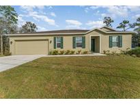 Charming single-story home with a well-manicured lawn, attached garage, and beautiful green shutters at 322 Dagama Ct, Kissimmee, FL 34758