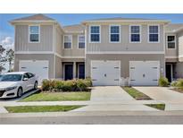 Charming townhomes with a white finish, garage, and landscaped front yard create a welcoming curb appeal at 421 Sedgewick Dr, Davenport, FL 33837