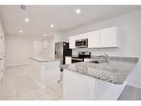 Modern kitchen features granite counters, stainless steel appliances, a center island, and bright lighting at 421 Sedgewick Dr, Davenport, FL 33837