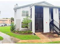 Two-story condo featuring stairs leading up to the second floor and lush green landscaping at 4882 S Semoran Blvd # 1408, Orlando, FL 32822