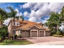 Beautiful home featuring a clay tile roof, stone accents, and a spacious three-car garage at 8950 Della Scala Cir, Orlando, FL 32836
