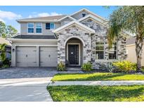 Beautiful two-story home with stone facade, three-car garage, and well-maintained landscaping at 10699 Petrillo Way, Winter Garden, FL 34787