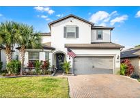 Charming two-story home showcasing a landscaped yard, brick driveway, and a welcoming two-car garage at 1298 Patterson Ter, Lake Mary, FL 32746