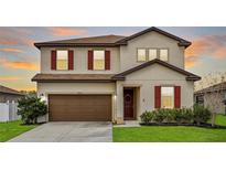 Two-story home with a two-car garage, neutral paint, red shutters, and well-maintained landscaping at 5607 Western Sky Pl, St Cloud, FL 34771