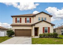 Two-story home with a brown roof, brown shutters, and a well-manicured lawn and landscape at 5607 Western Sky Pl, St Cloud, FL 34771