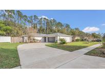 Charming single-story home featuring a well-manicured lawn and a spacious driveway leading to an attached two-car garage at 8691 Contoura Dr, Orlando, FL 32810