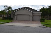 Beige home with a brick driveway and an attached two-car garage at 12126 Homestead Park Ln, Orlando, FL 32824