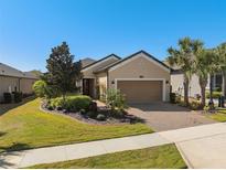 Charming single-story home featuring a well-manicured lawn, paver driveway, and tropical landscaping at 1392 Zeek Ridge St, Clermont, FL 34715