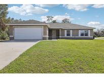 Charming single-story home featuring a two-car garage and a well-maintained front lawn with clear blue skies at 16060 Sw 21St Terrace Rd, Ocala, FL 34473