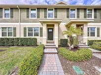 Inviting townhome exterior with manicured landscaping and a charming brick walkway leading to the front door at 16133 Pebble Bluff Loop, Winter Garden, FL 34787