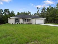 New home featuring a well-manicured lawn, neutral exterior paint, and a two-car garage at 2220 Sw 169Th Pl, Ocala, FL 34473