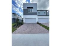 Modern townhome with gray and white exterior, featuring a brick driveway and well-maintained landscaping at 2244 Shadowland Loop, Winter Park, FL 32792