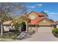 Stunning two-story home boasts a terracotta roof, three-car garage, and lush landscaping at 2442 Heritage Green Ave, Davenport, FL 33837
