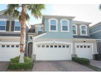 Inviting two-story home featuring a paver driveway, attached garage, and a mature palm tree in the front yard at 3557 Brighton Park Cir, Orlando, FL 32812
