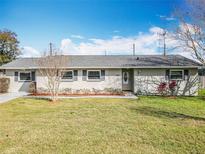 Charming single-story home boasts a well-maintained lawn, manicured landscaping, and classic shutters at 7565 Dockside St, Winter Park, FL 32792