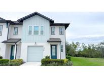 Charming two-story townhome with white facade, attached garage and dark trim, complimented with a lush landscaped yard at 1549 Discovery St, Davenport, FL 33896