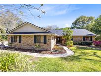 Charming single-story brick home with lush landscaping, mature trees and a welcoming walkway leading to the front door at 1575 Belfast Ct, Apopka, FL 32712