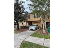 Charming tan two-story townhome with a private front entrance, driveway, and lush landscaping at 214 Artisan St # J, Orlando, FL 32824