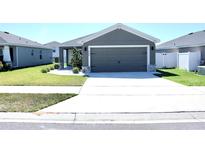 Charming single-story home with a well-manicured lawn, concrete driveway, and neutral gray exterior at 2294 Sunset Way, Davenport, FL 33837