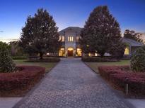 Elegant home with lush landscaping and a paved driveway leading to the grand entrance at twilight at 11306 Bridge House Rd, Windermere, FL 34786